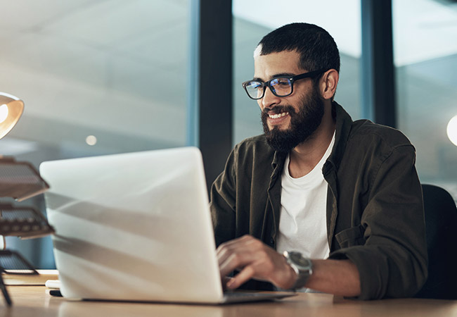 young man smiling at computer screen